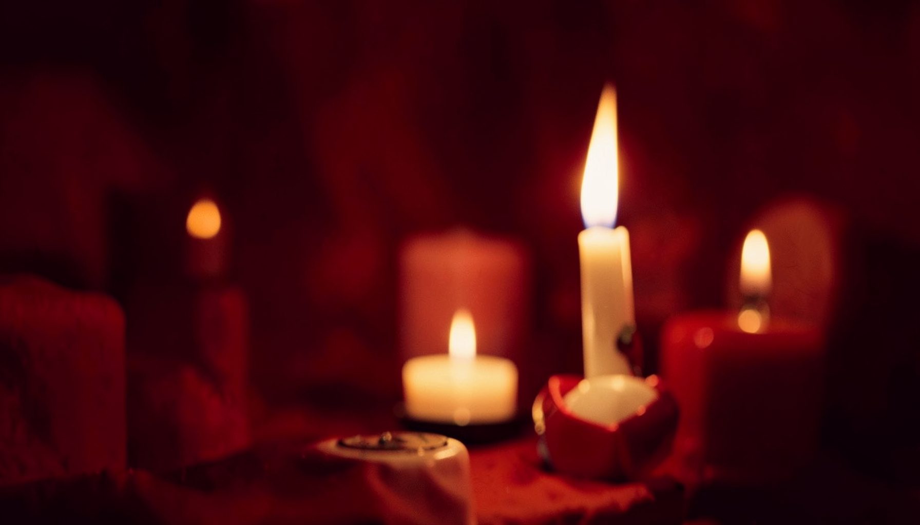 A contemplative Christmas album cover in deep crimson and ivory, with soft candlelight warmth