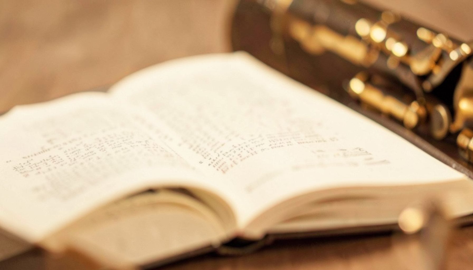 A warm-toned audiobook cover in cream and sepia, featuring an open book and a brass instrument in soft focus